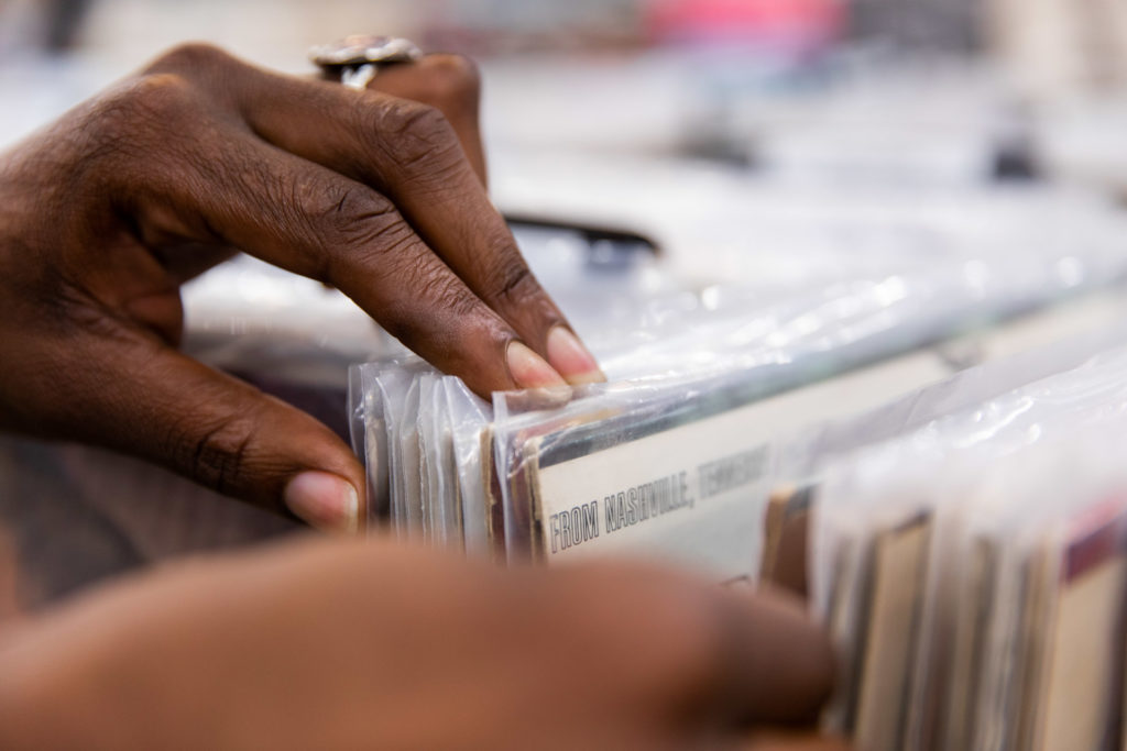 hand browsing through stacks of vinyl at a record store near you